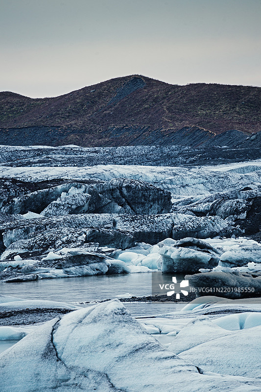 黄昏下的冰冻景观，远处的山脉散发着宁静，冰山、冰川、雪、冰岩、冰钻、冰川湖，自然，雪，冰岛，欧洲图片素材