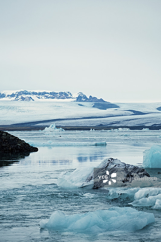 宁静的冰冷景观，漂浮的冰山和遥远的雪山，冰山，冰川，雪，冰岩，冰钻，冰川湖，自然，雪，钻石海滩，冰岛，欧洲图片素材