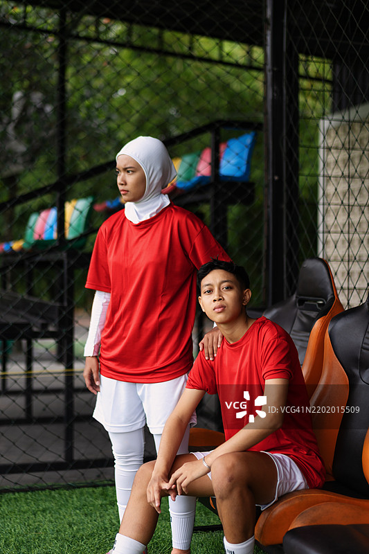 多样化的年轻印尼足球运动员自信地在场边摆姿势的肖像图片素材