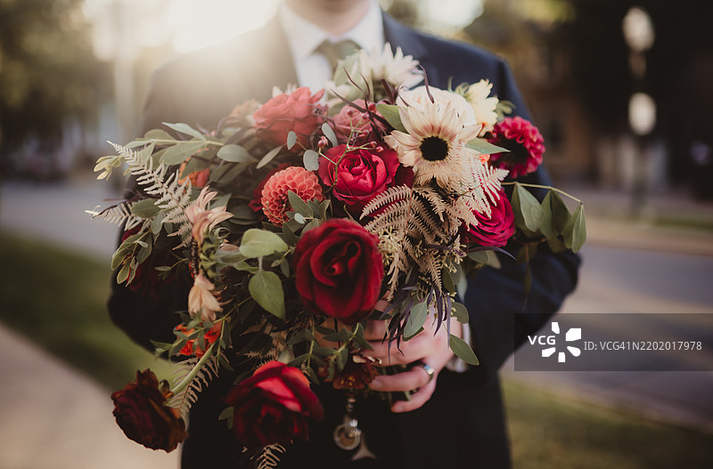男人在日落时分户外手持婚礼花束图片素材