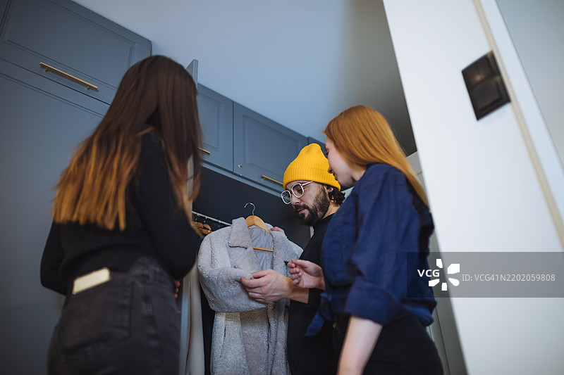 在现代衣橱环境中讨论外套选择的小组图片素材