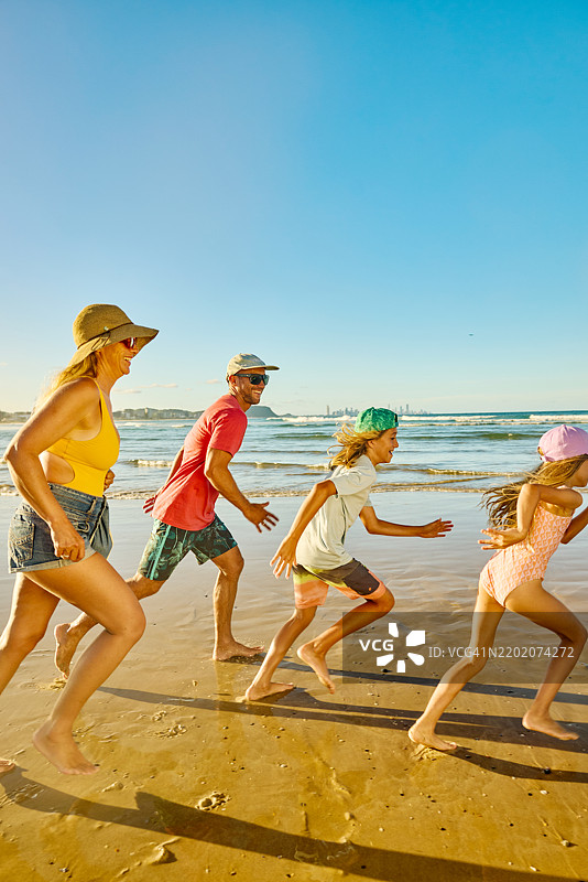快乐的家庭在澳大利亚的海滩上奔跑，享受夏季假期图片素材