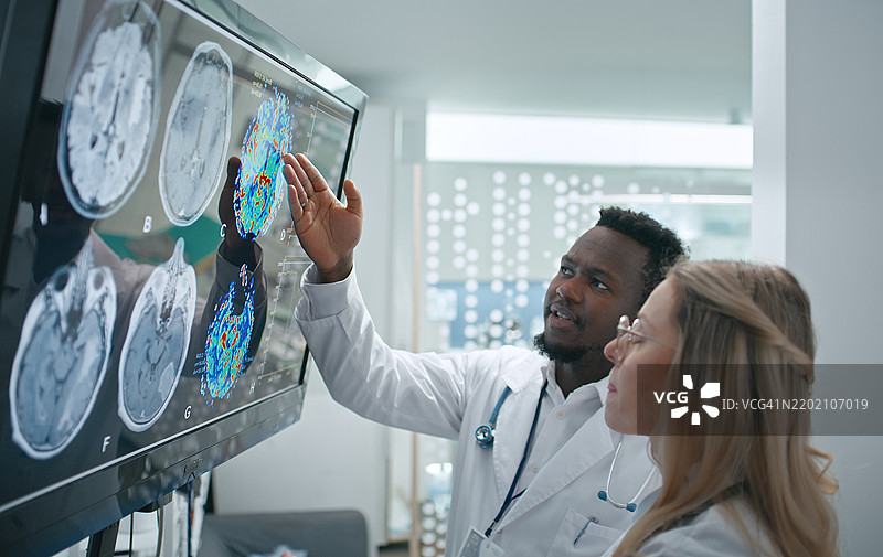 男医生和女医生仔细检查患者的头骨X光片，仔细观察细节以确定是否存在任何异常或需要关注的潜在问题。图片素材