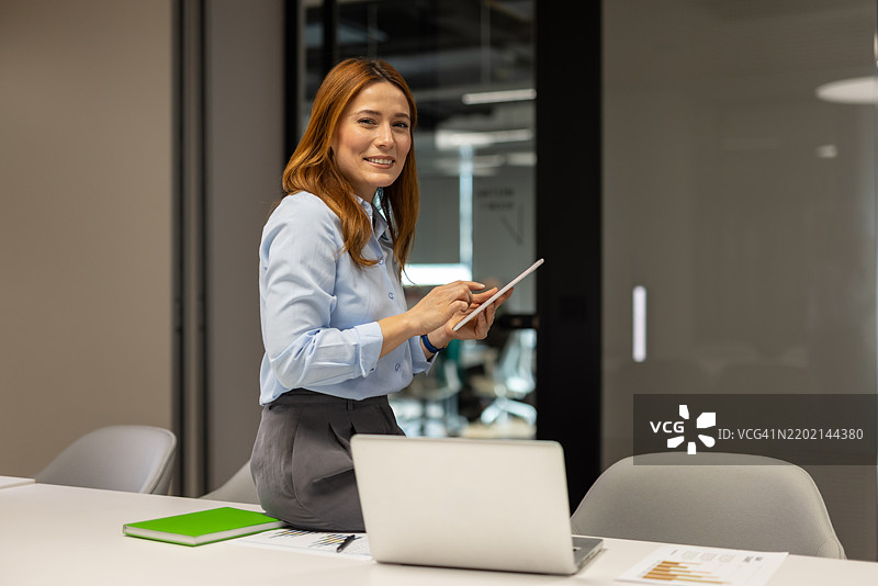 自信的女商人在办公室轻松坐着，使用数字平板电脑，展现现代商业责任的方式图片素材
