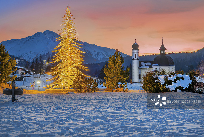 冬季黄昏时分,人工照明的冬季冷杉树与2797米的霍赫德尔山,位于奥地利蒂罗尔州的西费尔德高原。图片素材