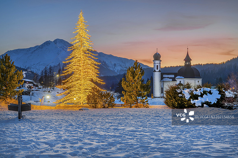 冬季黄昏时分,人工照明的冬季冷杉树与2797米的霍赫德尔山,位于奥地利蒂罗尔州的西费尔德高原。图片素材