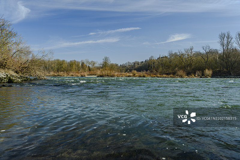 在蓝天下，河流在繁茂的河岸之间流淌，水面平静，重归自然的伊萨河，位于伊萨尔河畔的兰道。图片素材
