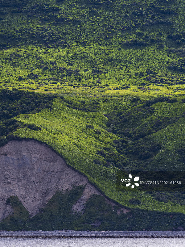 悬崖和绿色山丘映衬在水面上图片素材
