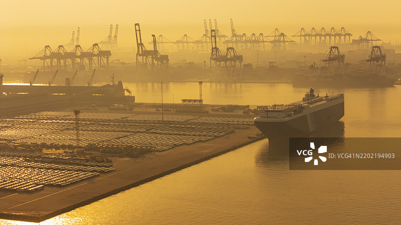 航拍视角下的大型滚装船（RoRo）在商业港口的码头上运输汽车，进行进出口业务物流、航运或货物运输。图片素材