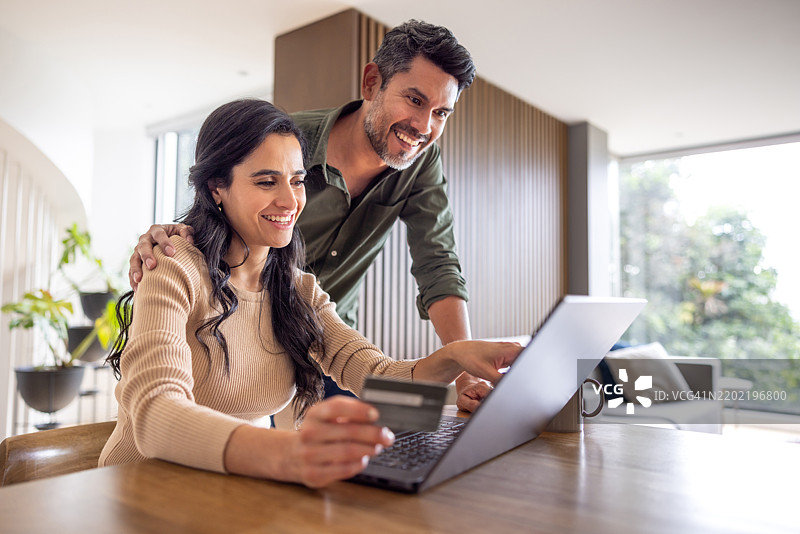 快乐的情侣在家网上购物并用卡支付图片素材