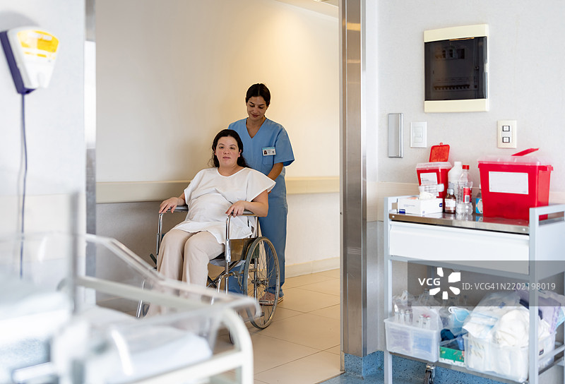 护士在产科医院推着一位孕妇坐在轮椅上图片素材
