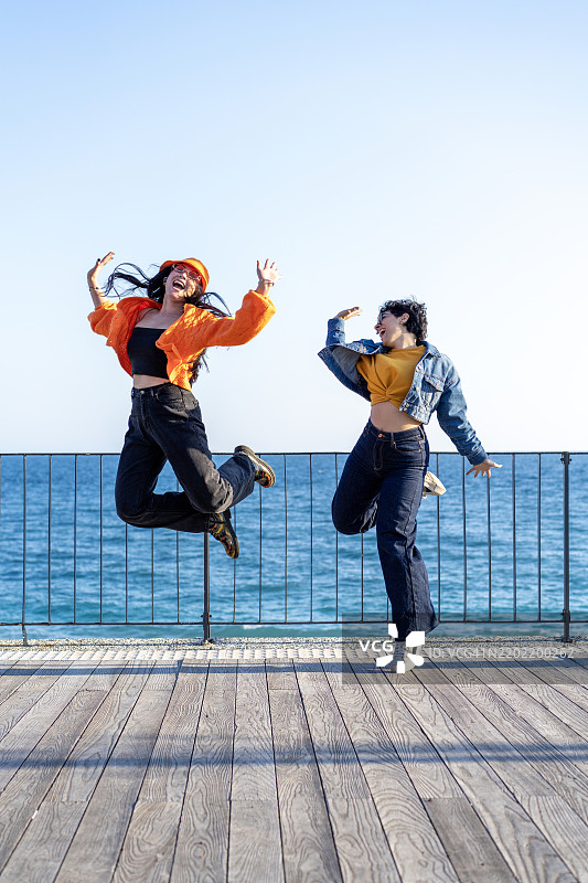 快乐的女性朋友们在海滩上跳跃图片素材