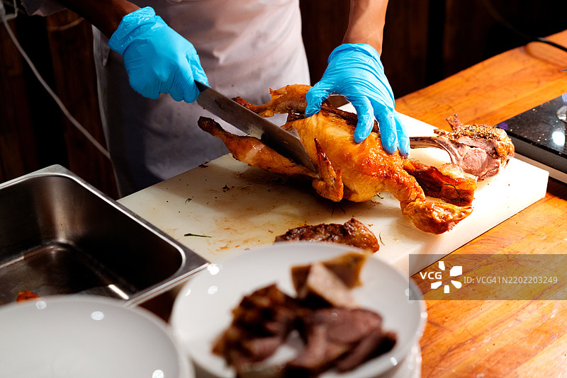 传统烤鸭正在被厨师切割。图片素材