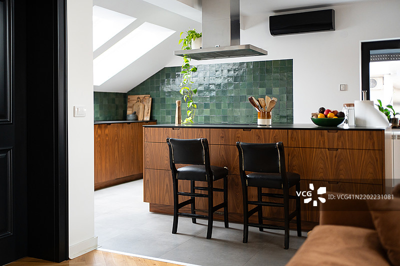 现代明亮的厨房内部，配有绿色瓷砖和木质岛台。图片素材