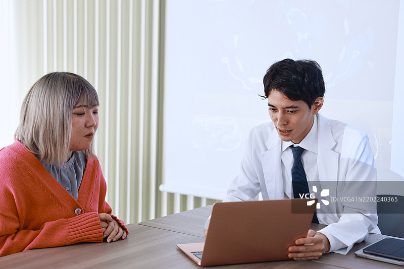 一位男性日本医生与女性患者讨论治疗方案的中景镜头图片素材