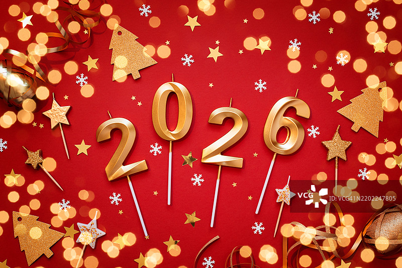 2026年的金色蜡烛与红色背景上的五彩纸屑。图片素材