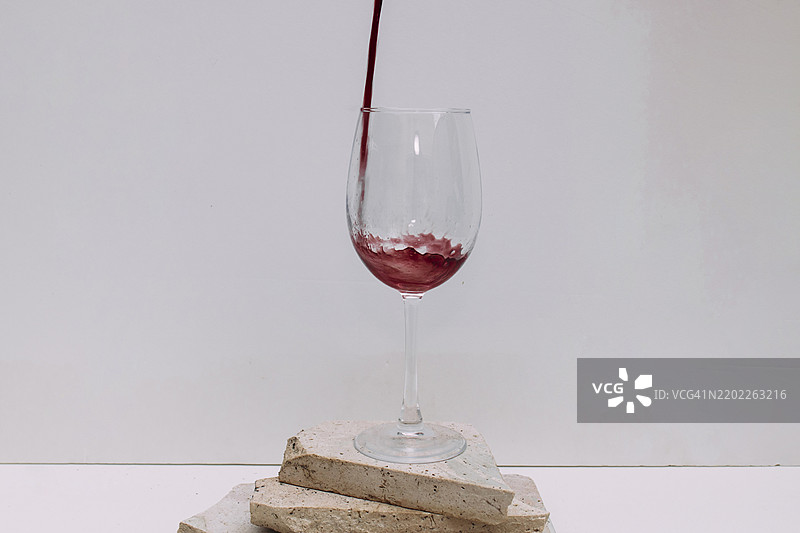 将红酒倒入石制底座上的酒杯中图片素材