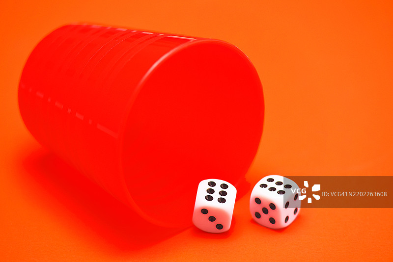 两个显示六点的骰子放在摇骰器旁边。图片素材