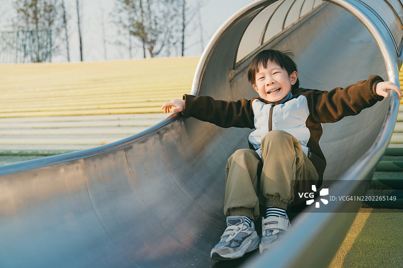 快乐的男孩在滑梯上玩耍图片素材