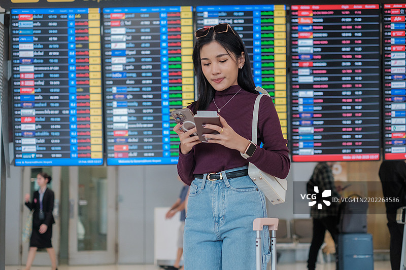 亚洲女性在等待飞机并查看航班时间表图片素材