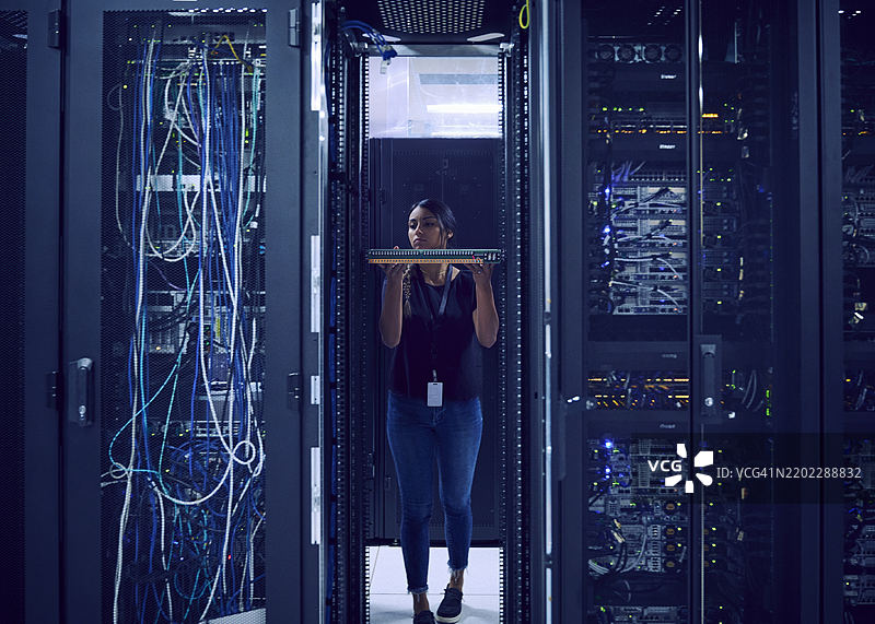 女性技术人员在服务器机房中手持硬盘图片素材