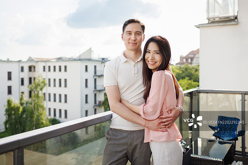 在阳台上站着的恩爱情侣，俯瞰美丽的城市景色图片素材