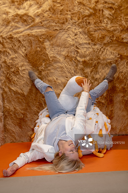 女人在橙色表面上顽皮地倚靠，背景有趣的纹理图片素材