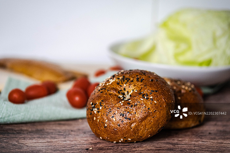 一盘撒有芝麻和番茄的贝果放在木桌上图片素材