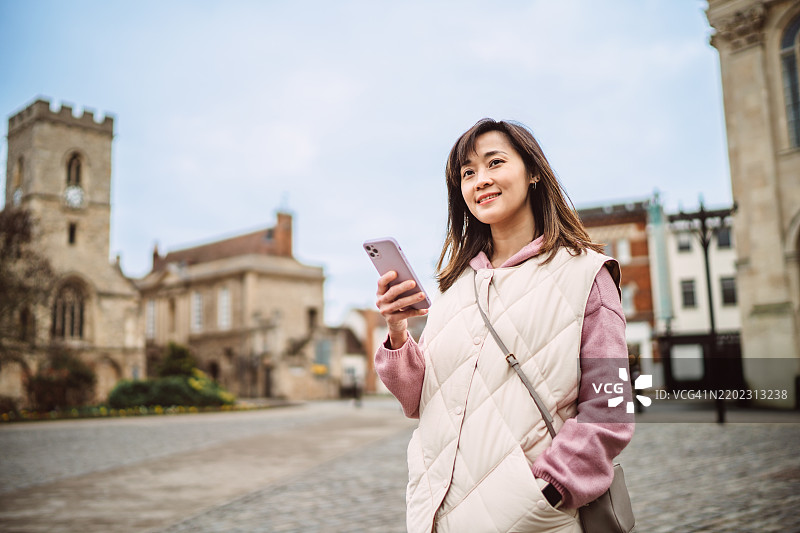 女性在旅行时享受城市漫步，同时使用智能手机图片素材