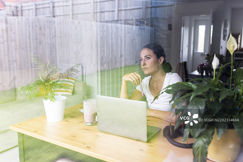 思考中的自由职业者坐在家中使用笔记本电脑图片素材