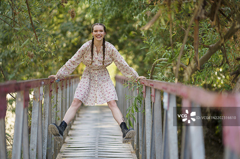 快乐的女人在树木前的桥上享受时光图片素材