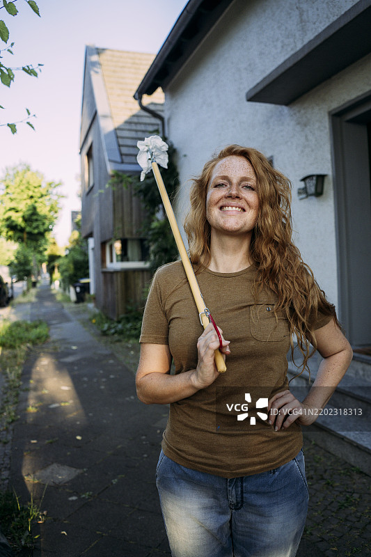 微笑的女性手持抓取工具站在街道上图片素材