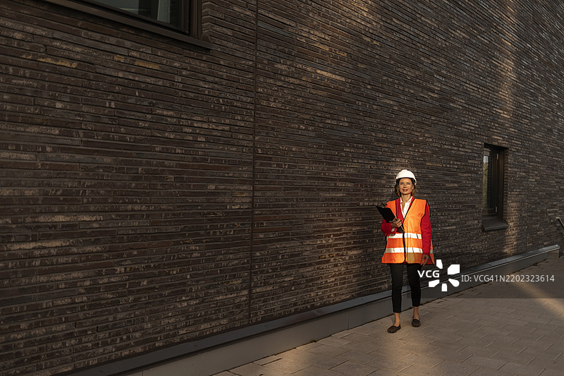 穿着反光背心的工程师站在墙边图片素材