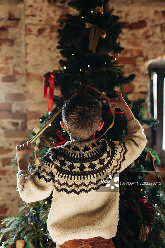 男孩在家中墙前装饰圣诞树图片素材
