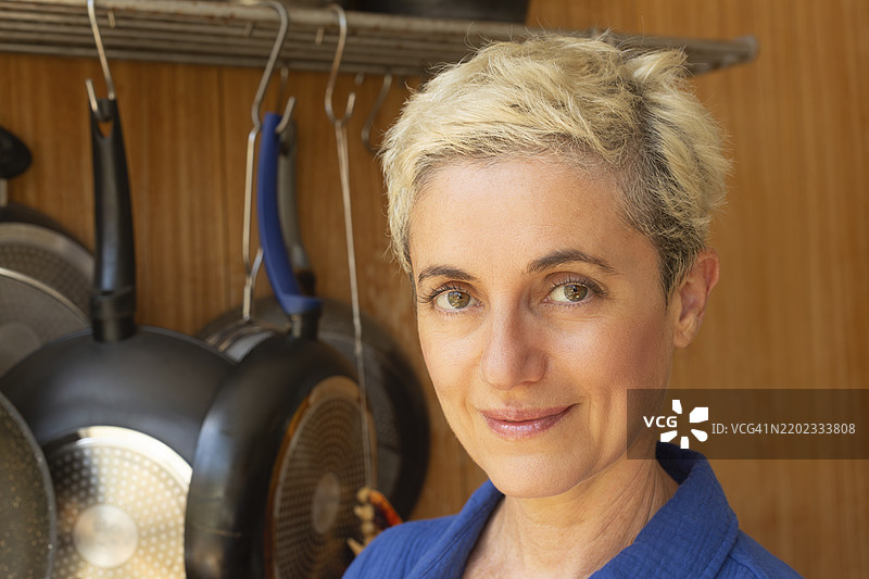 微笑的短发女性在厨房里与餐具相伴图片素材