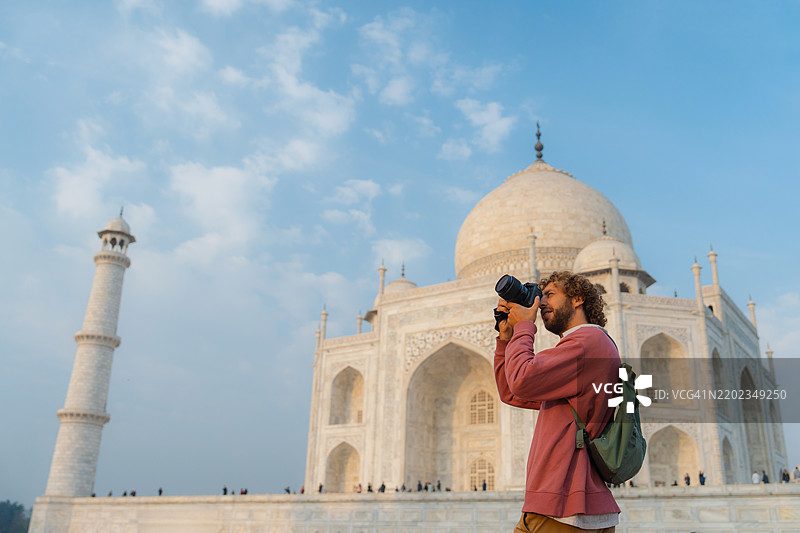 在印度旅行时，一名男子在泰姬陵附近用相机拍照图片素材