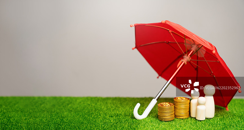 财产、生活、健康和金融保险概念，养老保险，家庭成员在红伞下与硬币站立，象征财务保护。图片素材