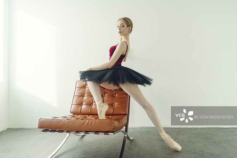 年轻的芭蕾舞者穿着舞裙和尖头鞋，坐在扶手椅上，位于俄罗斯西伯利亚的诺沃西比尔斯克。图片素材