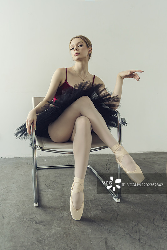 年轻的芭蕾舞者穿着舞裙和尖头鞋，坐在椅子上摆姿势，位于俄罗斯西伯利亚的诺沃西比尔斯克。图片素材
