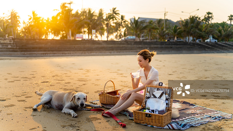 亚洲女性与她的狗在海边一起旅行。图片素材