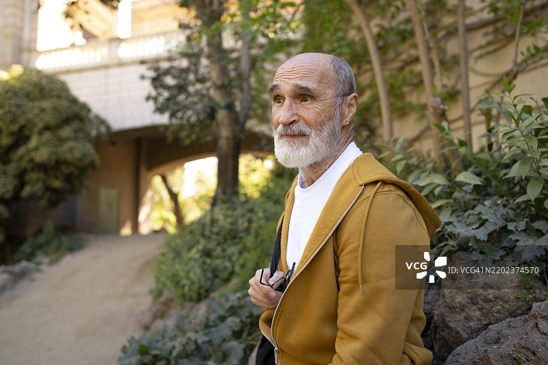 一位老年男子站在建筑物前的植物旁边图片素材