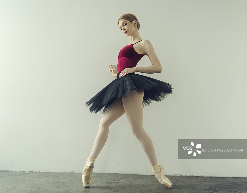 年轻的芭蕾舞者穿着舞裙和尖头鞋，靠在墙上摆姿势，展示芭蕾舞元素，位于俄罗斯西伯利亚的诺沃西比尔斯克。图片素材