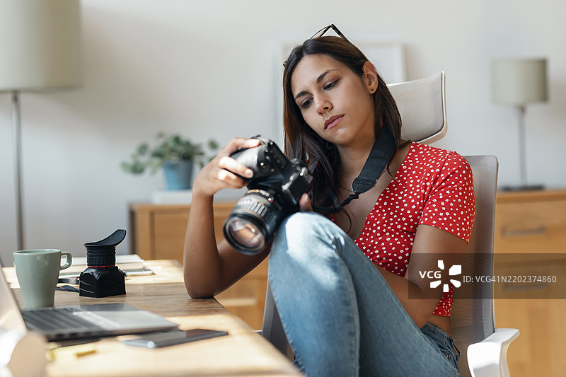 自由职业者在家办公桌上查看相机中的照片图片素材
