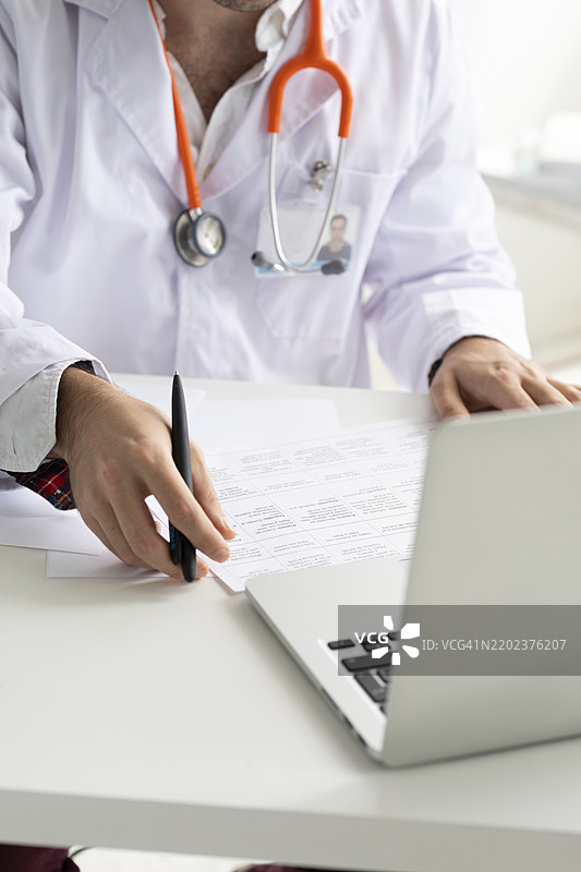 营养师在桌子上使用笔记本电脑并坐着查看文件图片素材