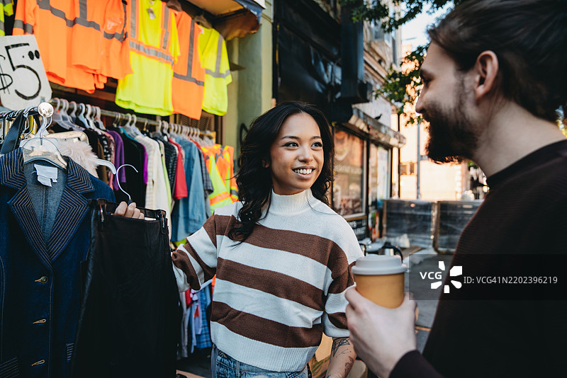 一对千禧一代情侣正在逛一家二手服装店图片素材