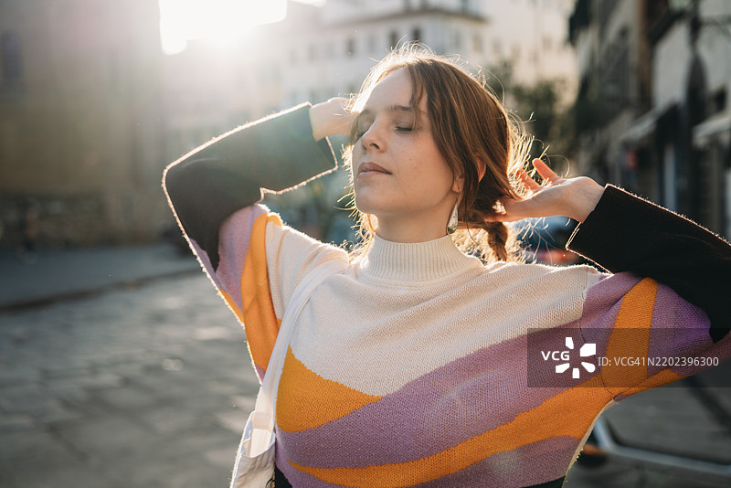 一位女性在日落时分在城市中放松。图片素材