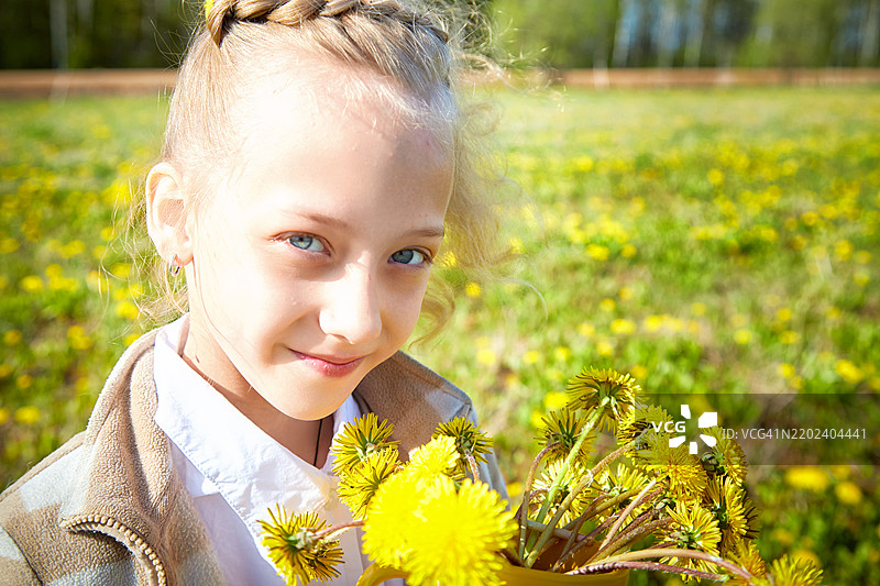 年轻女孩微笑着手捧一束蒲公英花。图片素材