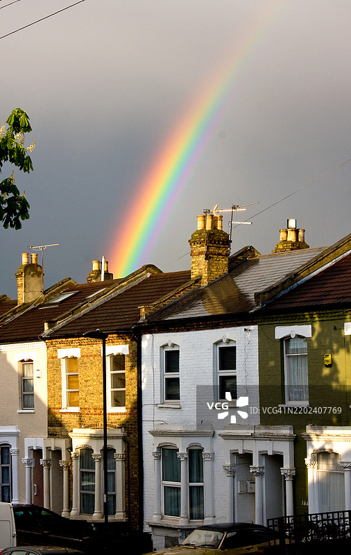 雨后阳光照耀下，梯田房屋后出现彩虹图片素材