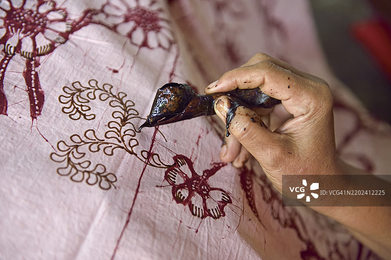 女性使用类似笔的工具（canting）在织物上涂抹热蜡，以在染色前创造图案，地点为印度尼西亚爪哇岛拉森的Kidang Mas Batik House工作坊。图片素材