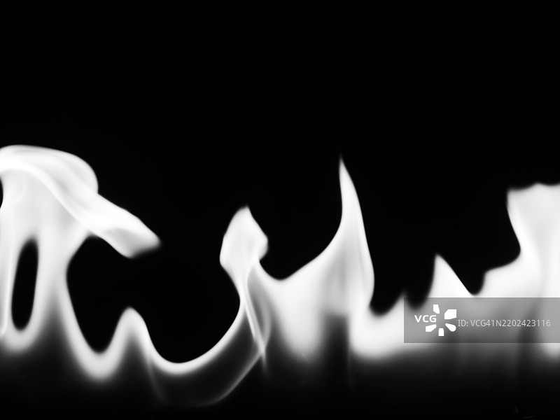 黑色背景上的白色火焰特写。虚焦照片。图片素材